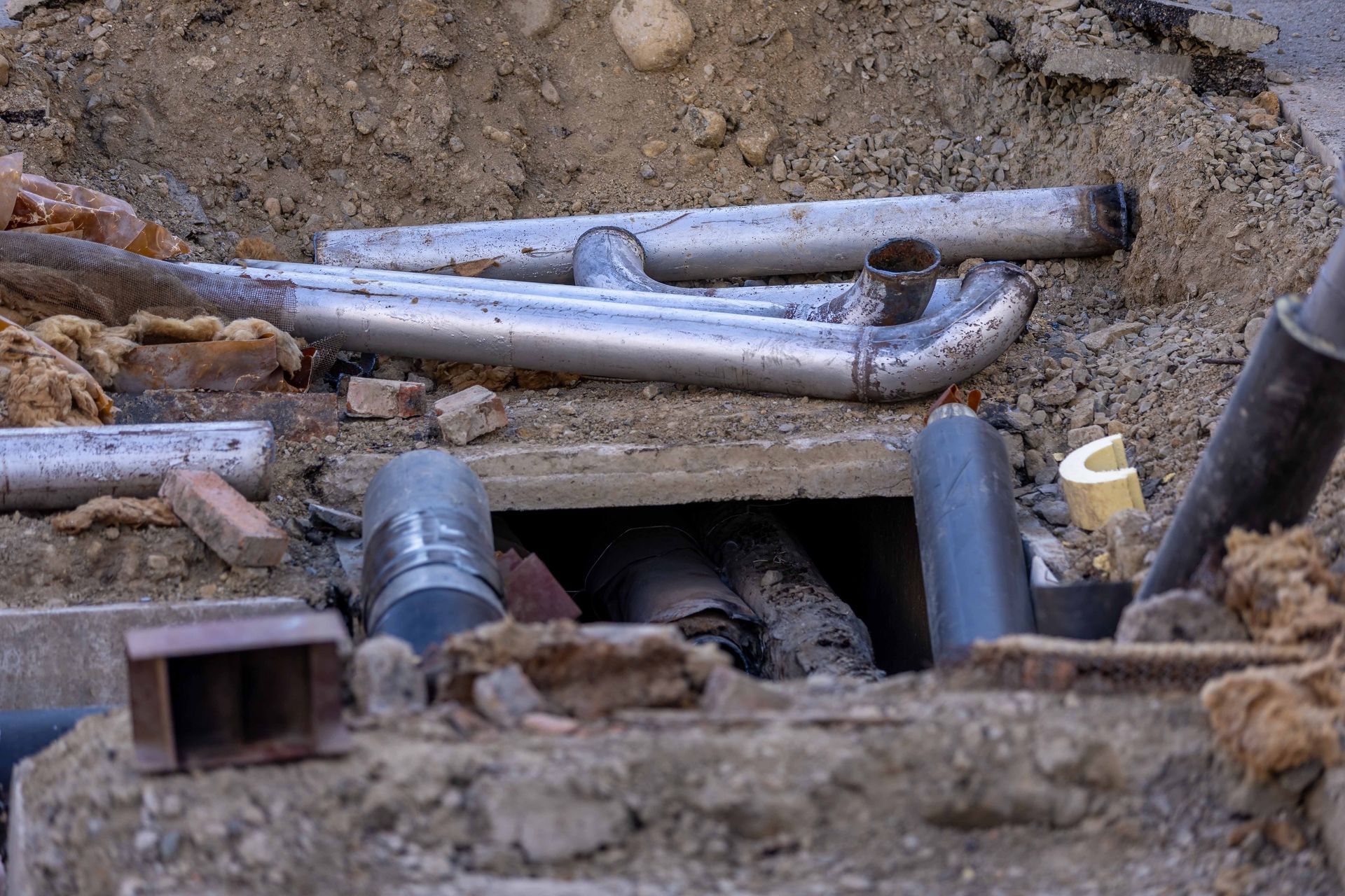 Close-up of urban pipe installation at a construction site, showing various pipes and materials.